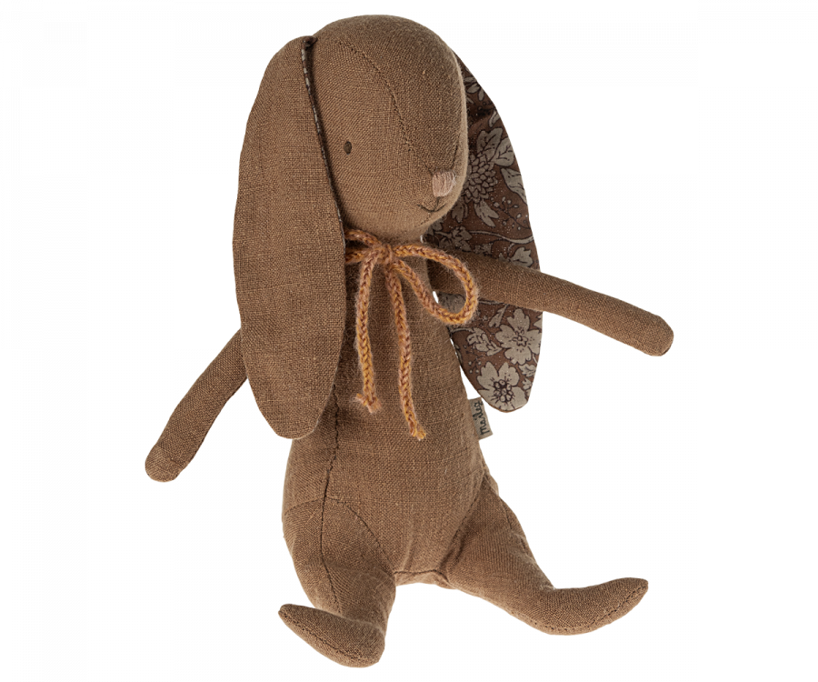 Maileg Bunny - Chocolate Brown: A soft bunny toy with floppy ears and a rustic orange bow around its neck. Made from recycled polyester, its inner ear lining features a floral pattern. The bunny, sitting upright with a neutral expression, also has magnets in its hands for added playfulness.