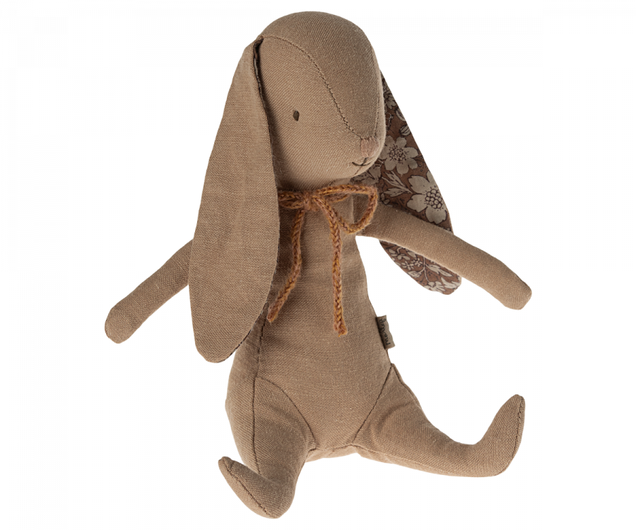 A soft bunny made from recycled polyester, this brown fabric stuffed toy features long floppy ears with a floral pattern on the inner side and a charming brown bow around its neck. With simple stitched facial features, outstretched arms and legs, it even has magnets in its hands for added fun. This is the Maileg Bunny - Powder!