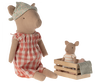 Two Maileg Pig - Girl toys are shown. The larger girl pig wears a floral headscarf and a red-checkered dress, sitting with legs extended. The smaller pig, dressed in a striped shirt, sits in a small wooden crate that is partially covered with fabric. They make up the sweetest pig family scene.