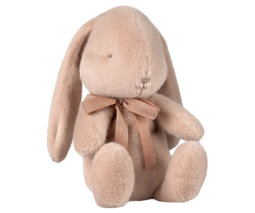 The Maileg Plush Bunny - Light Powder is a soft, plush toy with long ears and a sweet look, featuring closed eyes and a small stitched nose. It sits upright with a brown ribbon around its neck, made from plush fabric and polyester fillings. Available for pre-order, it ships in February.