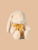 The PRE-ORDER Maileg Plush Bunny - Small Cream features long ears, a soft cream color, and sits upright. Made from recycled polyester, it dons a yellow ribbon around its neck against a light brown background. Ships in February.