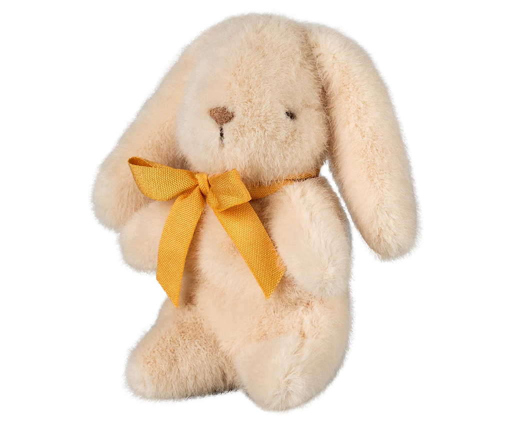 The PRE-ORDER: Maileg Plush Bunny - Mini Cream features a fluffy beige design, crafted from soft plush fabric. It sits upright with long ears framing a charming yellow bow around its neck. Ships in February.