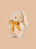 The PRE-ORDER: Maileg Plush Bunny - Mini Cream, made from soft recycled polyester with cream fur and long ears, is accented by a yellow ribbon around its neck and posed gracefully against a light brown background. Ships in February.