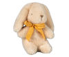 A soft Maileg Plush Bunny - Mini Cream, pre-orderable and shipping in February, sits upright. Crafted from recycled polyester, this beige bunny has floppy ears, a stitched black nose, and a bright yellow ribbon tied as a bow around its neck.