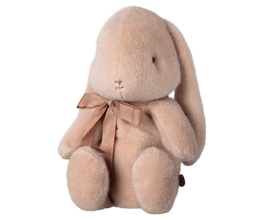 The PRE-ORDER: Maileg Plush Bunny - Medium Light Powder is a soft, eco-friendly bunny with a sweet minimalist design. It sits upright, features long floppy ears, has an embroidered face with a calm look, and is adorned with a brown ribbon. Crafted from recycled polyester, it ships in February.