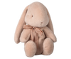 The Maileg Plush Bunny - Medium Light Powder features plush, soft beige fabric with long ears and a sweet expression. Decorated with a light brown bow around its neck, this eco-friendly bunny made from recycled polyester sits upright on a neutral background. Available for pre-order, ships in February.