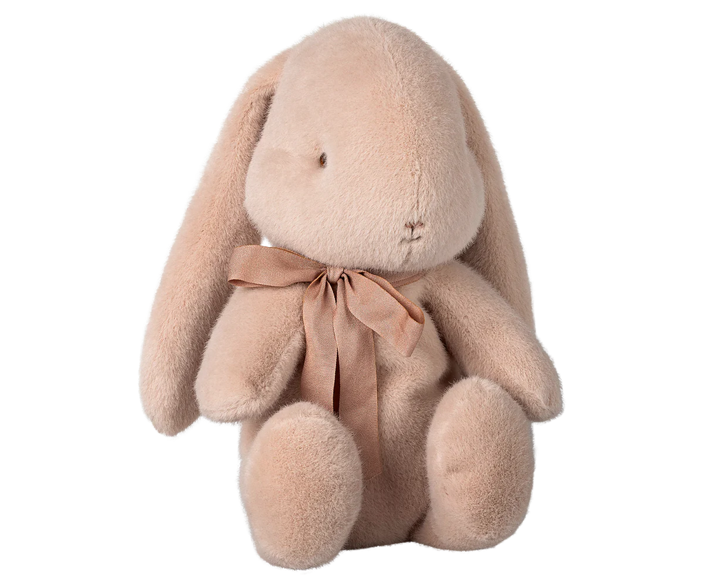 The Maileg Plush Bunny - Medium Light Powder features plush, soft beige fabric with long ears and a sweet expression. Decorated with a light brown bow around its neck, this eco-friendly bunny made from recycled polyester sits upright on a neutral background. Available for pre-order, ships in February.