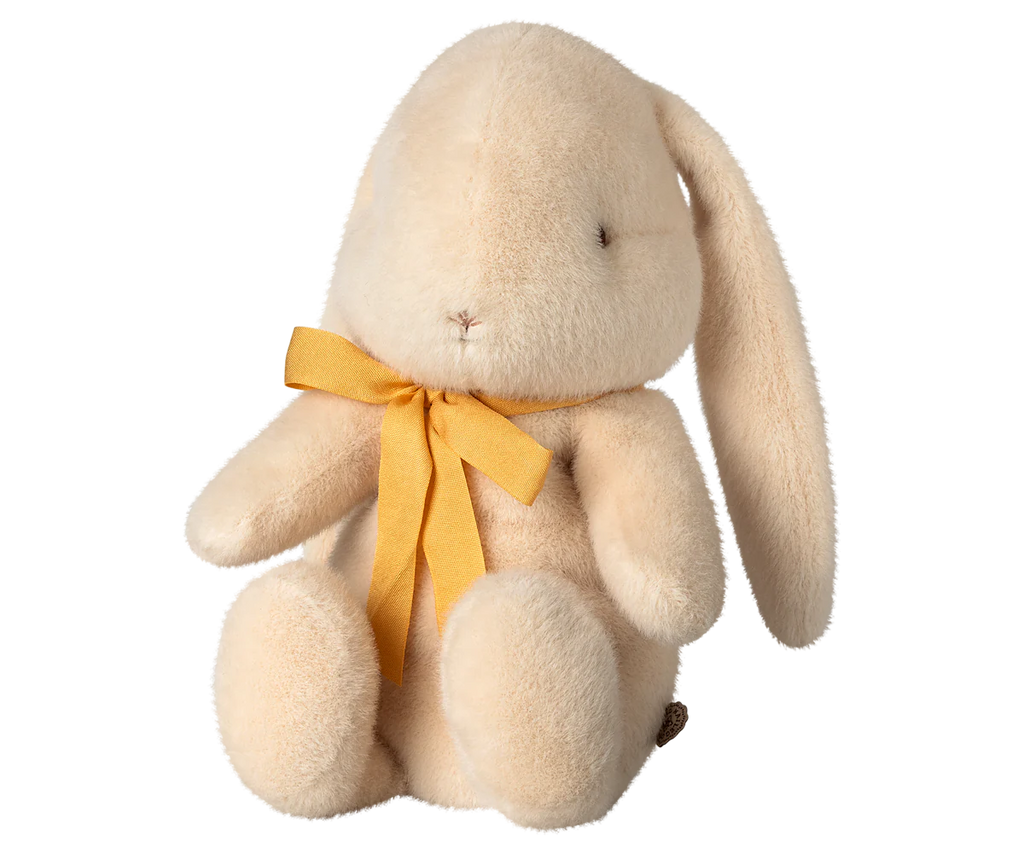 The Maileg Plush Bunny in Medium Cream, available for pre-order and shipping in February, is crafted from recycled polyester. This eco-friendly bunny features long ears, a yellow neck ribbon, and a charmingly simple expression while sitting upright.