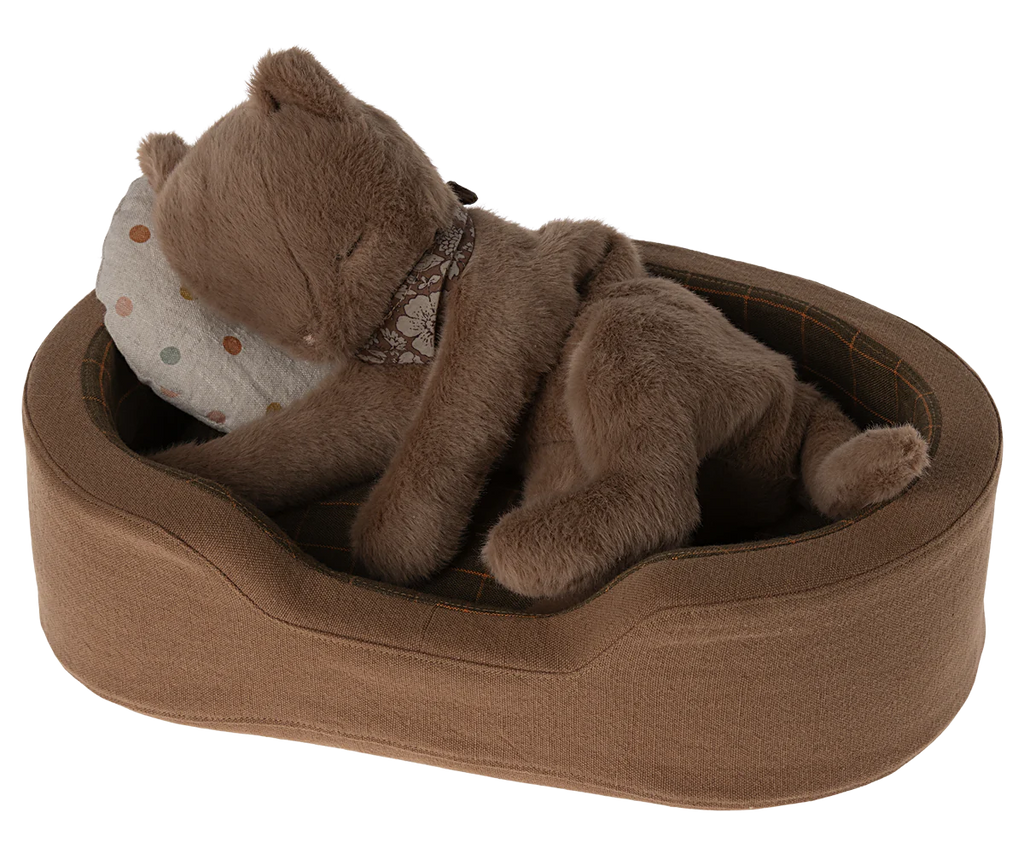 A Maileg Plush Kitten, Nougat (ships in approximately one week) lies in a brown, plush pet bed with its head resting on a white pillow adorned with colorful polka dots. The adorable toy cat appears to be sleeping comfortably, creating a cozy and cute scene that would make a perfect addition to any pet collection.