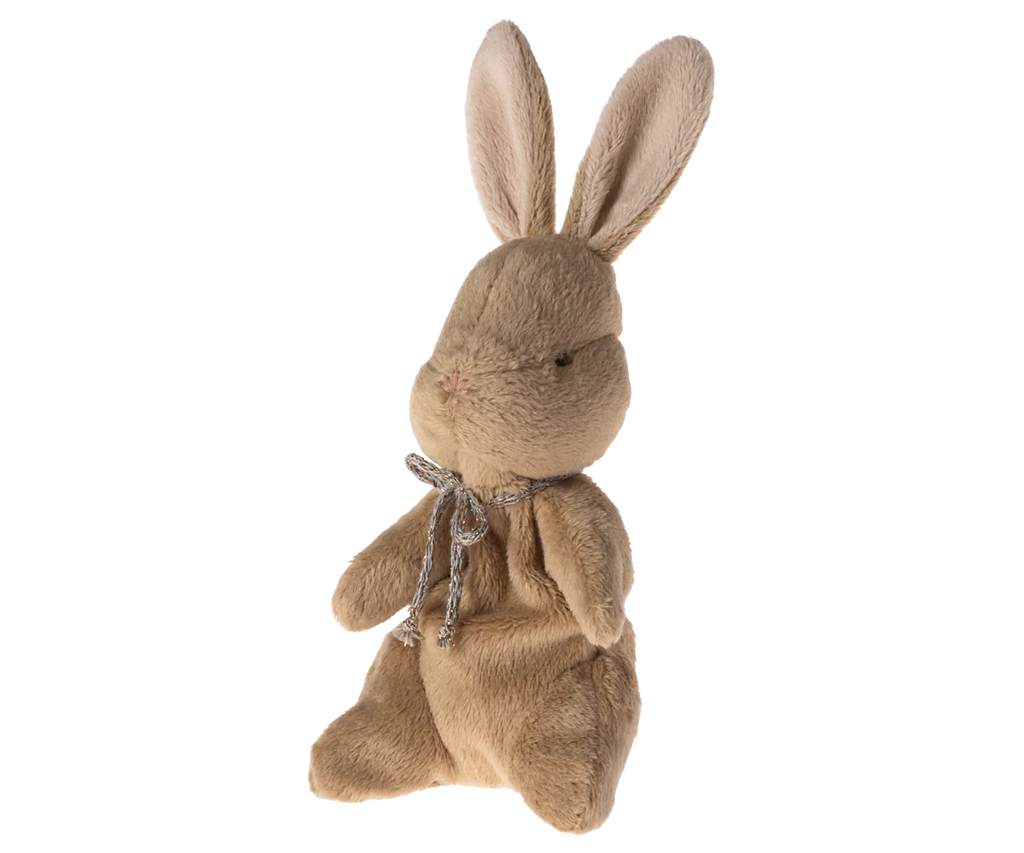 The Maileg My First Bunny - Brown is a light brown plush with long ears, black stitched eyes, and a silver bow, sitting upright against pastel stripes—perfect as a soft plush for “my first bunny” moments.