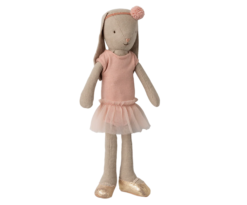 The Maileg Bunny, Size 2 - Classic, wears a ballet suit and rose skirt, featuring a pink headband with pompom and gold shoes. The doll stands upright against a neutral background.
