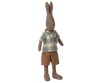 The Maileg Rabbit, Size 2 - Brown, wears a blue and beige plaid shirt with brown shorts and stands upright against a plain background. Ideal for pairing with miniature rabbit furniture.