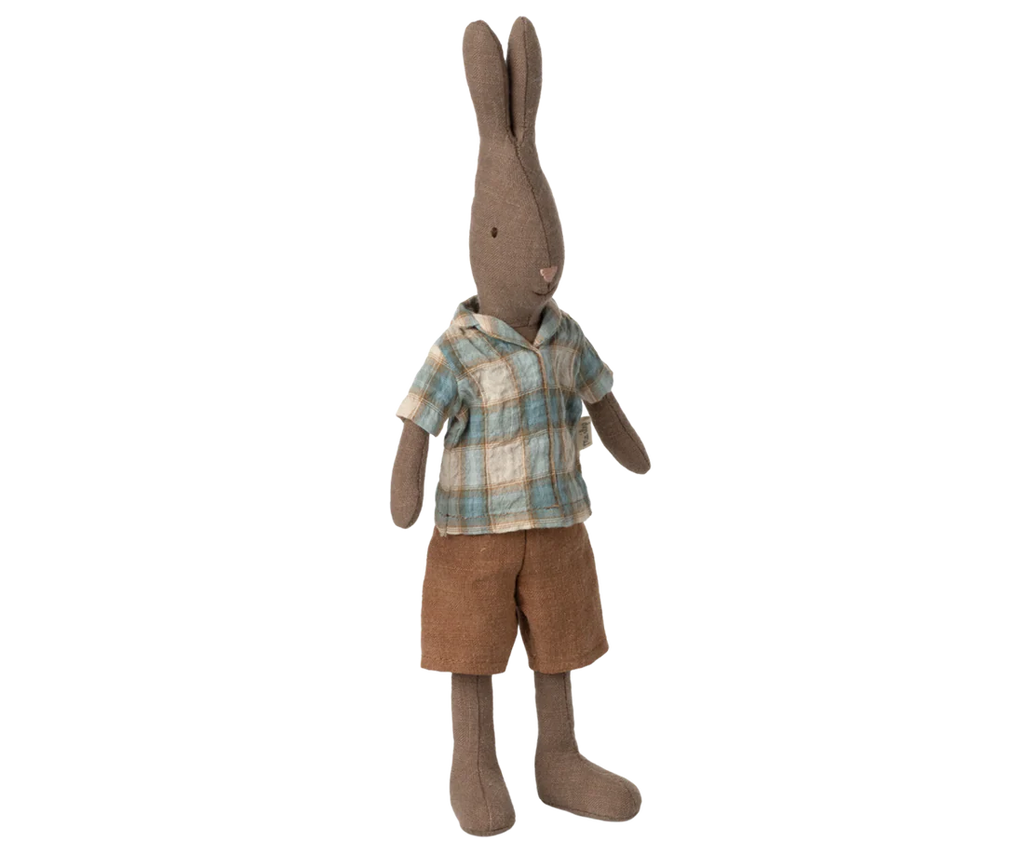 The Maileg Rabbit, Size 2 - Brown, wears a blue and beige plaid shirt with brown shorts and stands upright against a plain background. Ideal for pairing with miniature rabbit furniture.
