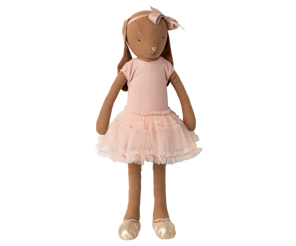 The Maileg Bunny, Size 3 in Chocolate Brown, wears a rose ballet suit and skirt, standing against a striped, blurred background.