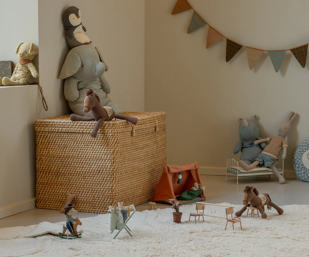 A cozy children's room features the Maileg Pony, Small—a soft brown cotton/linen plush—alongside a woven basket, toy tent, miniature chairs and beds. Soft lighting and a fun pennant banner add to the warm, playful atmosphere.