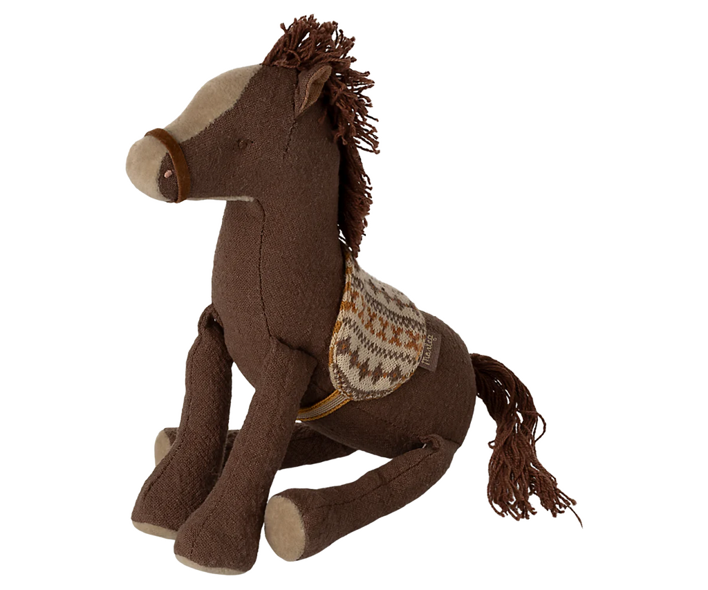 The Maileg Pony, Small is a soft brown plush toy made from cotton/linen, featuring a patterned saddle, light snout, and sits upright with a brown yarn mane and tail.