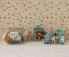A Maileg Fireplace, Mouse is set beside a toy mouse holding a stick, with a cozy bed, armchair, and breakfast on a tiny table—all arranged against animal-patterned wallpaper for charming dollhouse accessory inspiration.