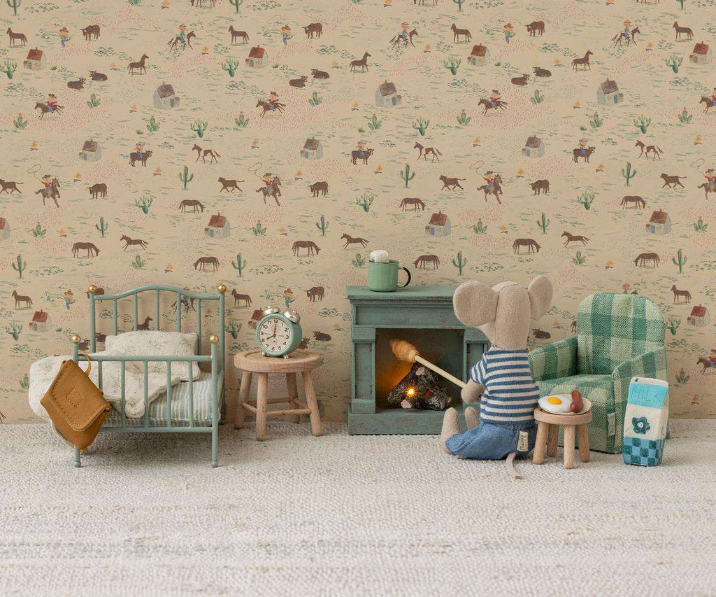 A Maileg Fireplace, Mouse is set beside a toy mouse holding a stick, with a cozy bed, armchair, and breakfast on a tiny table—all arranged against animal-patterned wallpaper for charming dollhouse accessory inspiration.