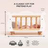 Wooden Dolls Cot in white with natural wood spindles, featuring dimensional labels, FSC certification logos, and a soft bedding set for roleplay.