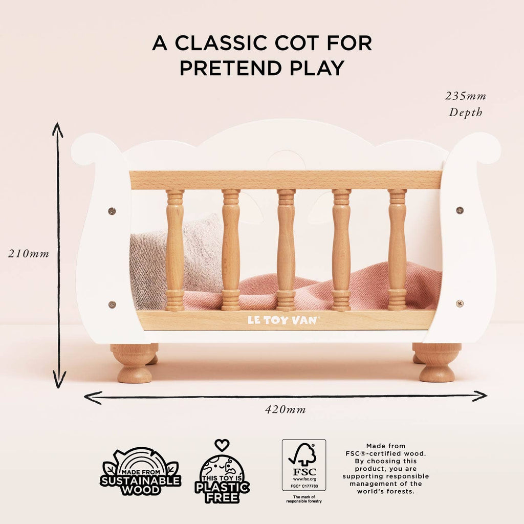 Wooden Dolls Cot in white with natural wood spindles, featuring dimensional labels, FSC certification logos, and a soft bedding set for roleplay.