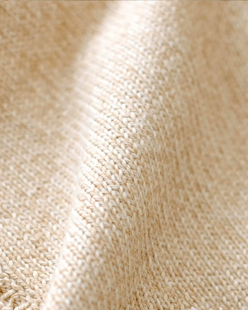 Close-up of Cuddle + Kind Organic Cotton Baby Bear Lovey in Honey, showing its soft, textured beige weave and visible fibers—perfect as a fair trade baby gift or cozy organic comfort item with gentle folds and shadows.