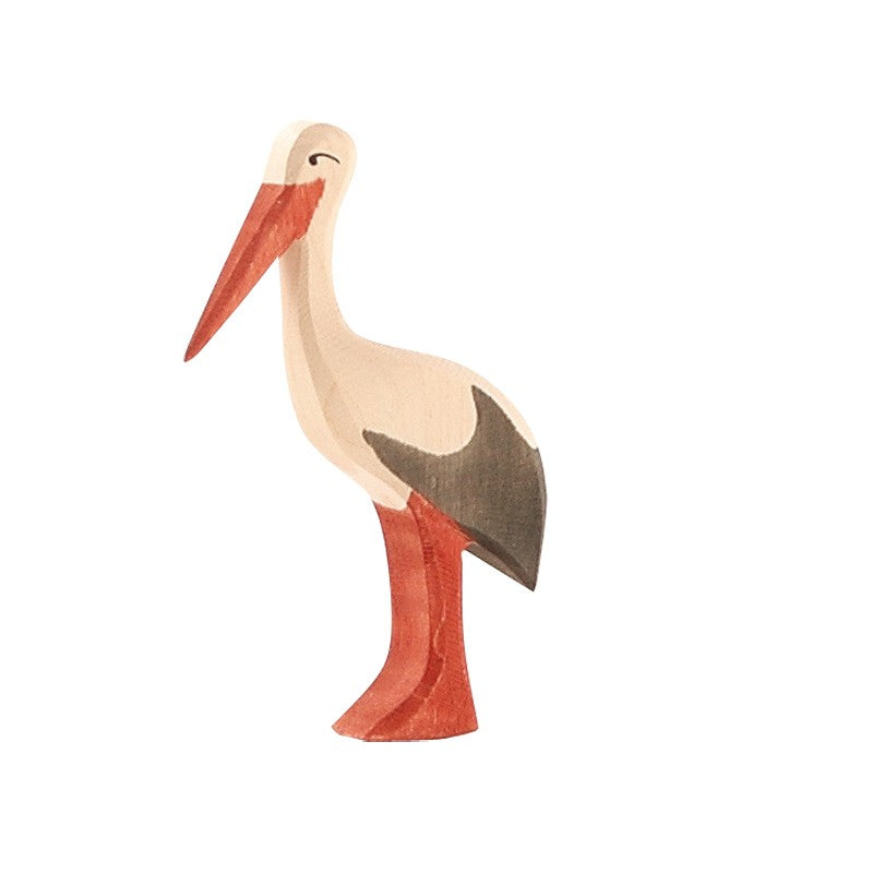 An Ostheimer Stork wooden figurine, skillfully handcrafted, is showcased against a plain white backdrop. The stork features a long, pointed red-orange beak and legs, with its body and wings adorned in natural wood hues, white, and grey. This exquisite piece is made using sustainably sourced materials.