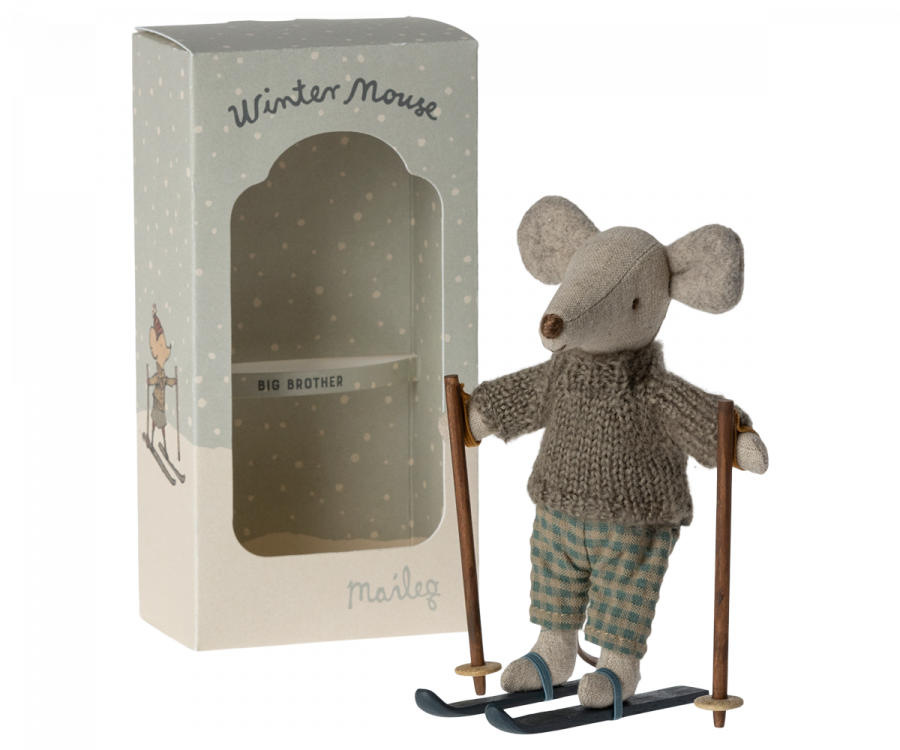 A grey toy mouse dressed in a knitted sweater and checkered pants stands on skis with poles made from recycled polyester. Next to it is a white box labeled "Maileg Christmas Winter Mouse With Ski Set, Big Brother" with an illustration of a mouse skiing and the words "Big Brother" printed on the clear window.