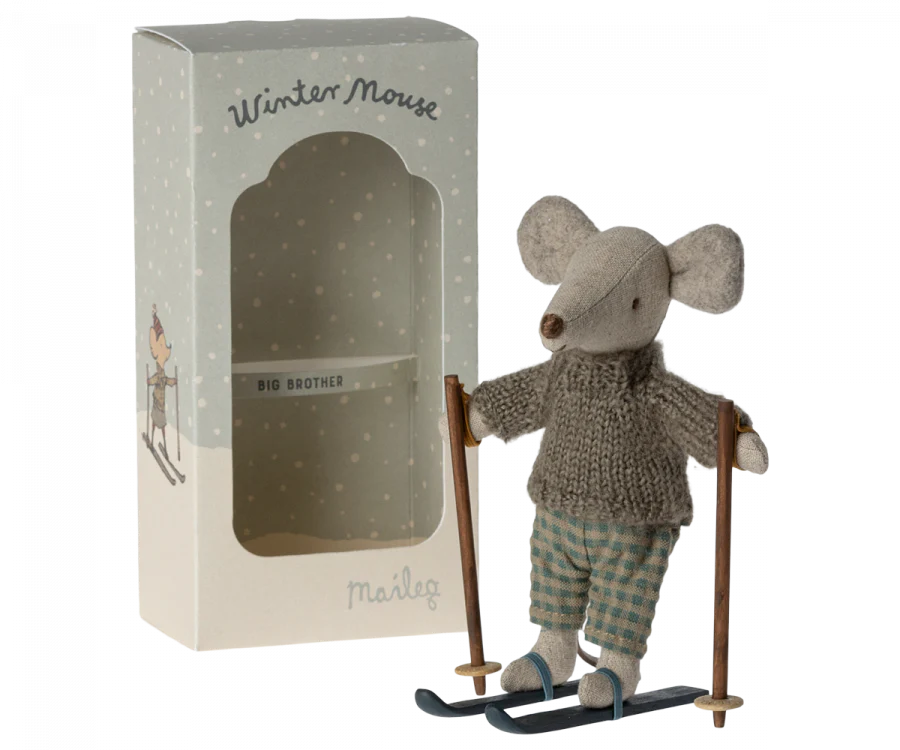 This delightful children's toy, part of the Maileg Ski Lounge Set, features a small stuffed mouse wearing a knit sweater and plaid pants, poised on skis with poles in hand. It comes packaged in a decorative box labeled "Winter Mouse," adorned with an adorable illustration.