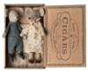 A vintage cigar box repurposed as a display case holds two stuffed mice dolls from the Maileg Set - Sleepover At Grandparents. One mouse is dressed in blue checkered overalls and black shoes, while the other wears a floral dress. The lid of the box features retro-style text and graphics advertising cigars.