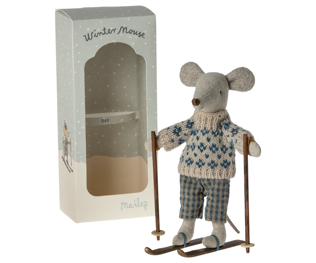The Maileg Winter Mouse with Ski Set, Dad, features a charming dad mouse in a blue-and-white sweater and plaid pants standing on skis with poles, alongside a decorated box labeled “Winter Mouse” and “Dad.”.