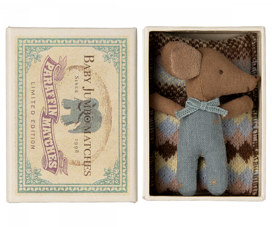 A small, brown fabric baby mouse with a bow tie, dressed in overalls, lies in a colorful matchbox labeled "Maileg Sleepy Wakey Baby Mouse In Matchbox - Blue" alongside a knitted blanket. The Maileg matchbox features vintage-style packaging with an elephant illustration.