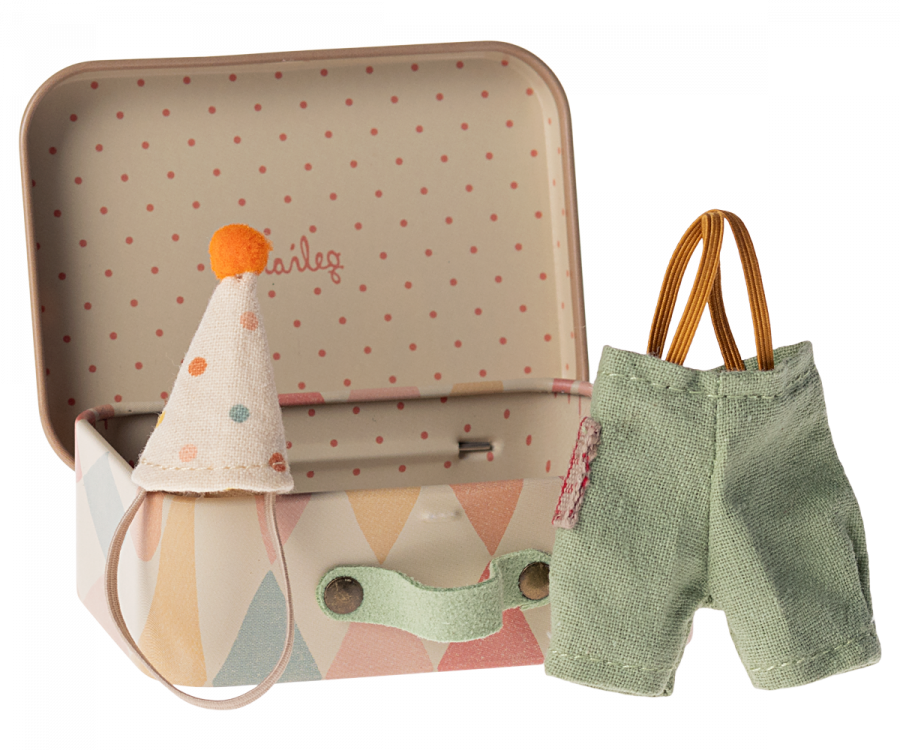 A small metal suitcase with a pastel diamond pattern is open, revealing a polka-dotted interior. Next to the suitcase, there is a small, pointy hat with a pompom on top and a pair of tiny green overalls with suspenders, perfect for Maileg Clown Clothes In Suitcase, Little Brother Mouse.