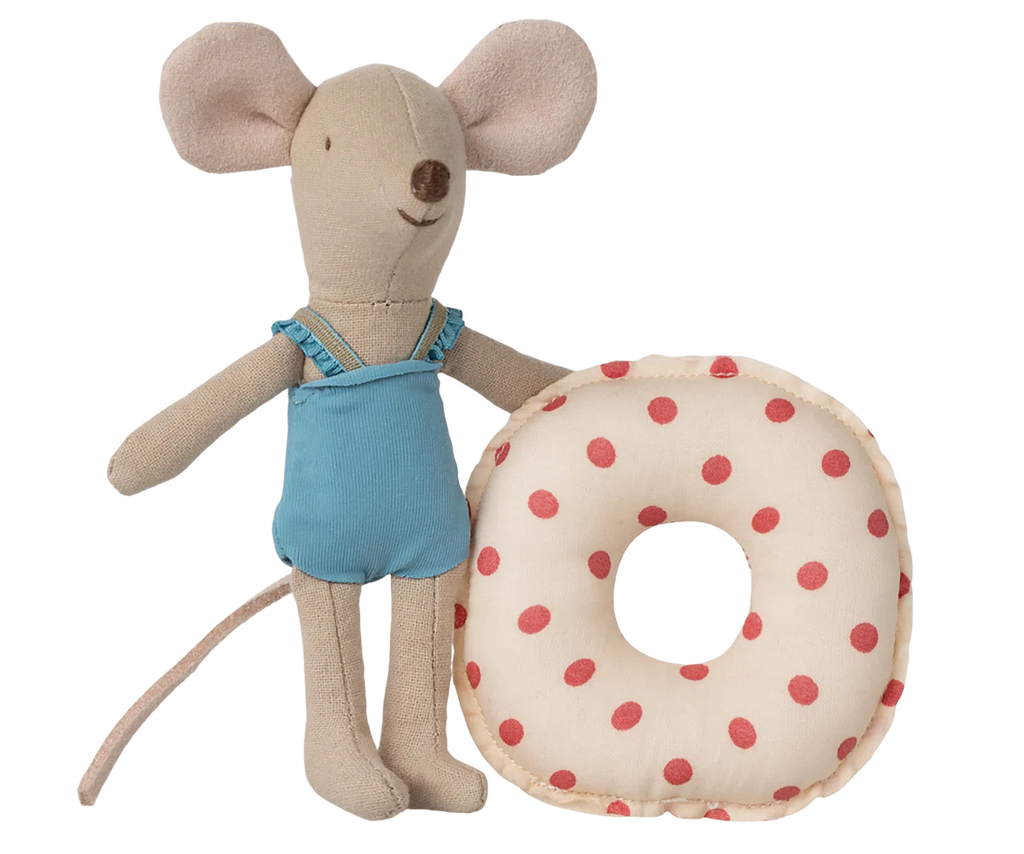 The Maileg Beach Mouse With Float, Little Sister - Red Dot features a smiling mouse in a blue swimsuit with large ears and a long tail, standing next to a soft, round, red polka dot float—perfect for playful summer fun.