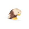 An Ostheimer Bird - Bald Eagle, Sitting: a handcrafted wooden figure with painted brown wings, white head, and yellow beak and feet, displayed on a white surface.