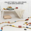 The American Wooden Car Set is displayed on a curved train track on a white floor, with a bench, pillow, and blanket in the background. Text above reads: "Collect them all and create your own adventure.