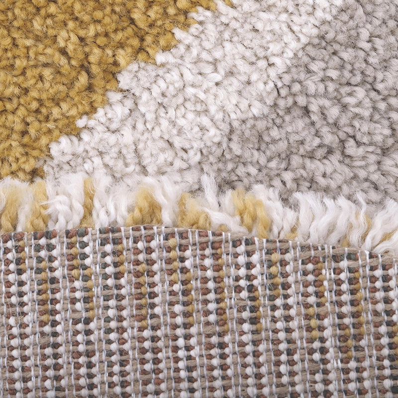 Close-up of the Bohemian Rainbow Children's Rug - Final Sale, featuring yellow, white, and grey fluffy sections on top, patterned brown, white, and yellow threads underneath, and a playful white fringe at the edge.