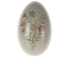 An oval-shaped Maileg Easter Egg, decorated with detailed, colorful flowers and leaves designed by Dorthe Mailil, set against a soft grey striped background.