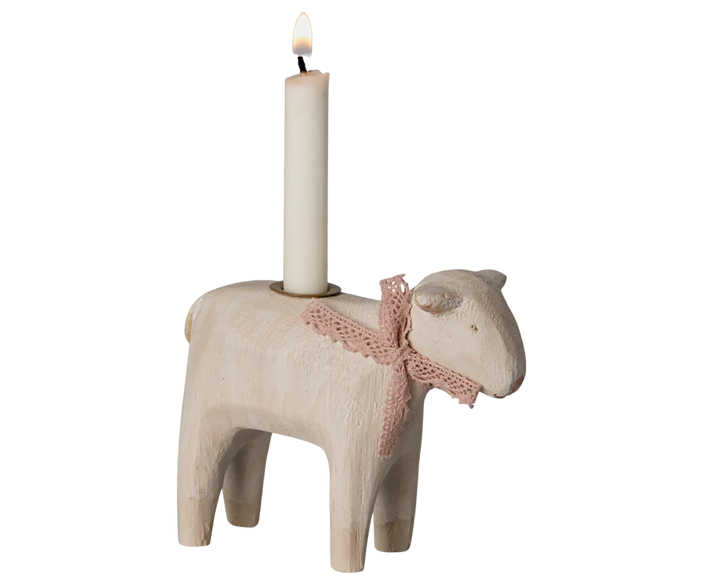 The PRE-ORDER Maileg Wooden Candle holder - Rose Lamb holds a lit white candle on its back. Ideal for Easter, this charming piece has a pink crochet ribbon around its neck, adding whimsy and craftsmanship to your festive decor. Ships late January.