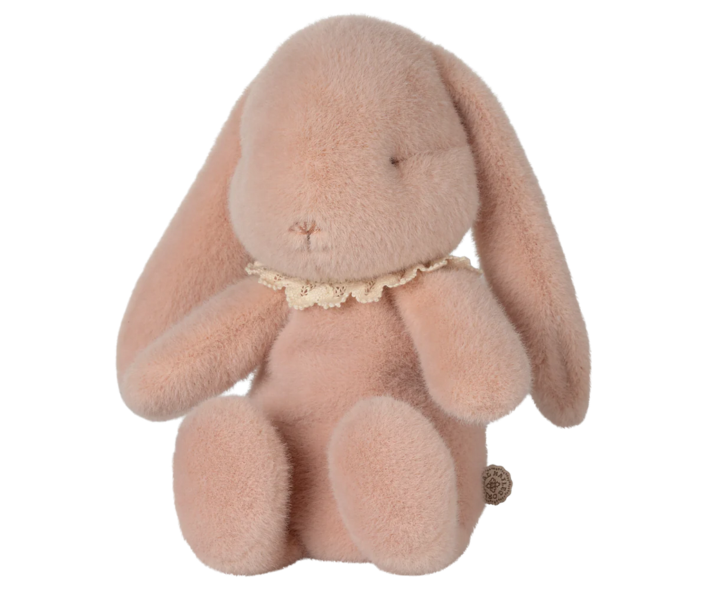 The pre-order Maileg Easter Egg With Bunny in powder pink features a soft plush bunny made from recycled polyester, with long ears, closed eyes, and a lace collar. It sits upright, highlighting its fluffy texture and contains PE pellets for stability. Ships in February.