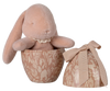 A pink plush bunny is nestled inside the Maileg Easter Egg With Bunny - Powder, a beige, patterned egg-shaped container made from recycled polyester with floral and rabbit designs. The matching lid features a beige bow. Ships in February.