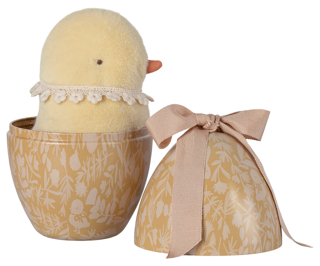 The PRE-ORDER: Maileg Easter Egg With Chick, shipping in February, includes a plush yellow chick with a lace collar nestled inside a decorative egg-shaped container made of recycled polyester. This container showcases a floral pattern and is topped with a pink bow.