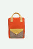 A Sticky Lemon Backpack Medium | Envelope | Campfire Orange is shown: a medium-sized, campfire orange backpack with beige handles and a front pocket. The front pocket has a yellow flap with a button and a brown checkered section underneath. Made from recycled PET material with a waterproof lining, this backpack is both stylish and eco-friendly. The background is white.