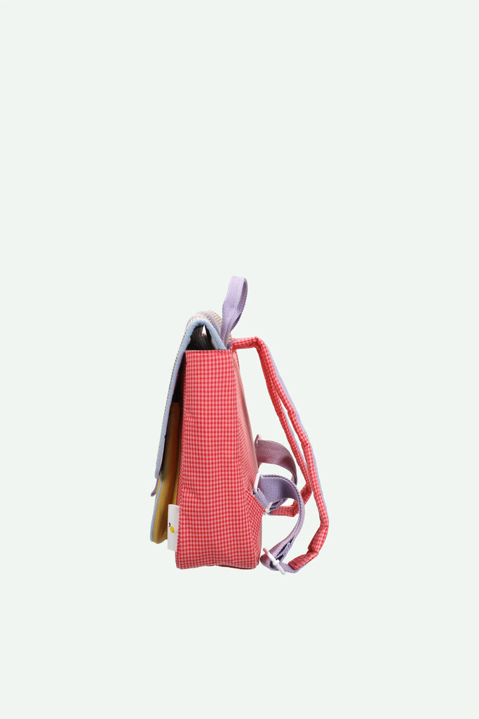 A side view of the Sticky Lemon School Bag | Lemon Tree | Gingham Flower + Rose, a children’s backpack featuring small red and white gingham checks, purple straps, and waterproof nylon material, set against a plain white background.