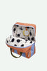 A medium-sized Sticky Lemon Backpack in Stripes (Cloud Blue + Maple Whirl) features brown and light blue stripes, unzipped to reveal a white interior with a black pear pattern and waterproof lining. The bag has olive green handles and a yellow tag attached inside.