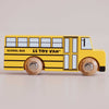Introducing the No. 47 GT285 Rufus | Made in England—a charming retro wooden school bus in classic yellow, featuring “SCHOOL BUS” and “LE TOY VAN” labeling, black detailing, robust wooden wheels, and black windows. Perfect for inspiring imaginative journeys with timeless American style against a plain backdrop.