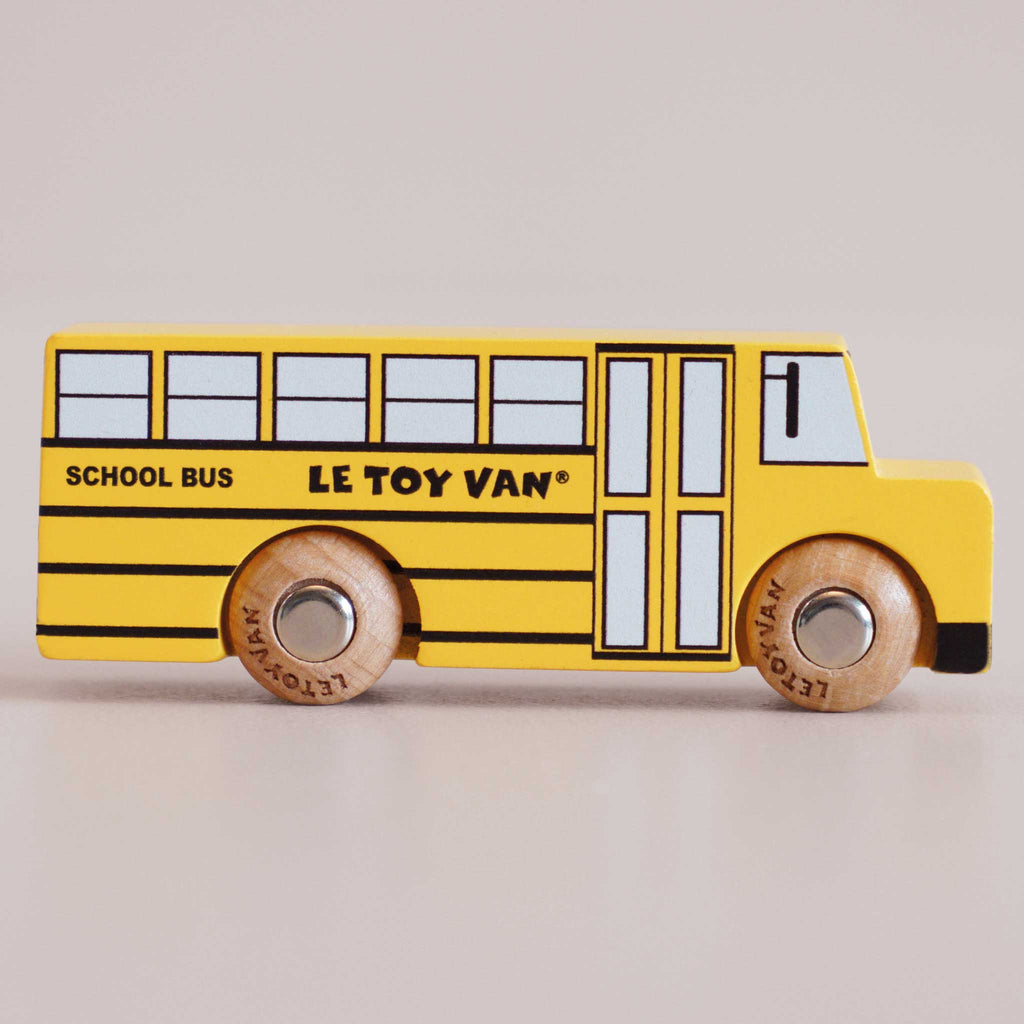 Introducing the No. 47 GT285 Rufus | Made in England—a charming retro wooden school bus in classic yellow, featuring “SCHOOL BUS” and “LE TOY VAN” labeling, black detailing, robust wooden wheels, and black windows. Perfect for inspiring imaginative journeys with timeless American style against a plain backdrop.