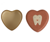 Two heart-shaped objects are shown. The one on the left is a golden metal heart-shaped container with an open lid. The one on the right is a Maileg Tooth Box with a smiling tooth illustration on the surface, evoking childhood memories of small baby teeth.