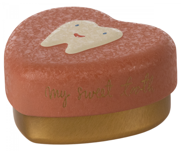 A Maileg Tooth Box with a textured surface. The lid is a light coral color and features a cute tooth illustration with a smiling face. The words "My sweet tooth" are printed in gold script on the side, perfect for holding small baby teeth and cherished childhood memories.