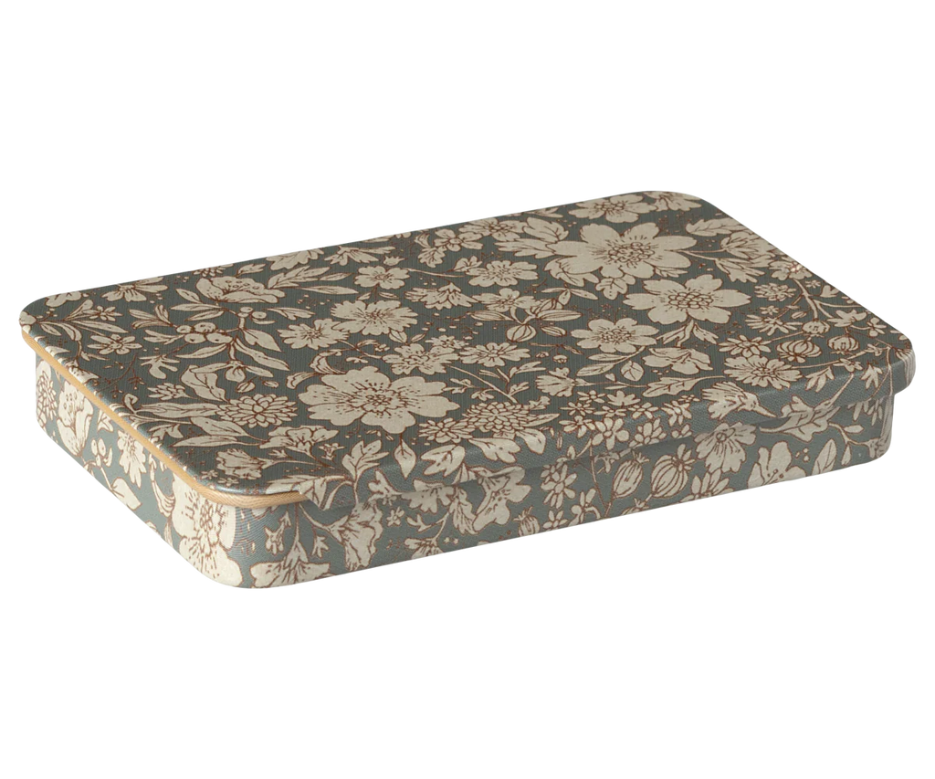 The Maileg Metal Box with a sliding lid is decorated with an intricate vintage-style floral pattern in shades of beige and dark grey. The detailed flowers and leaves cover the entire surface of the metal box, creating an elegant and antique appearance.