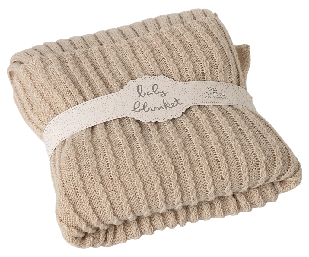 The Maileg Baby Blanket is a folded, beige knitted blanket with a cozy ribbed texture, wrapped in a cream band labeled "baby blanket" and the size.